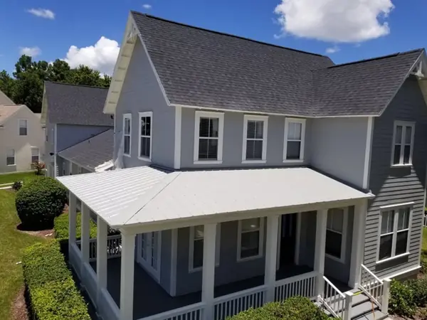 Gray two-story home with a freshly painted metal porch roof