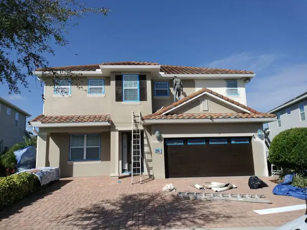 Two-story stucco home during prep for paint